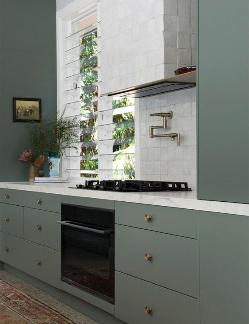 green toned kitchen with black appliances